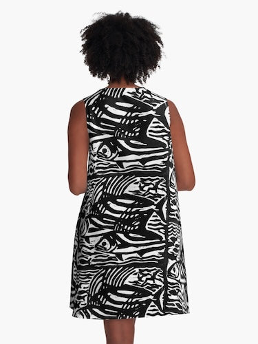 Person wearing a sleeveless dress with abstract black and white pattern on a plain background