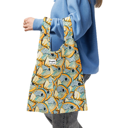 Person holding a colorful reusable bag with fish pattern